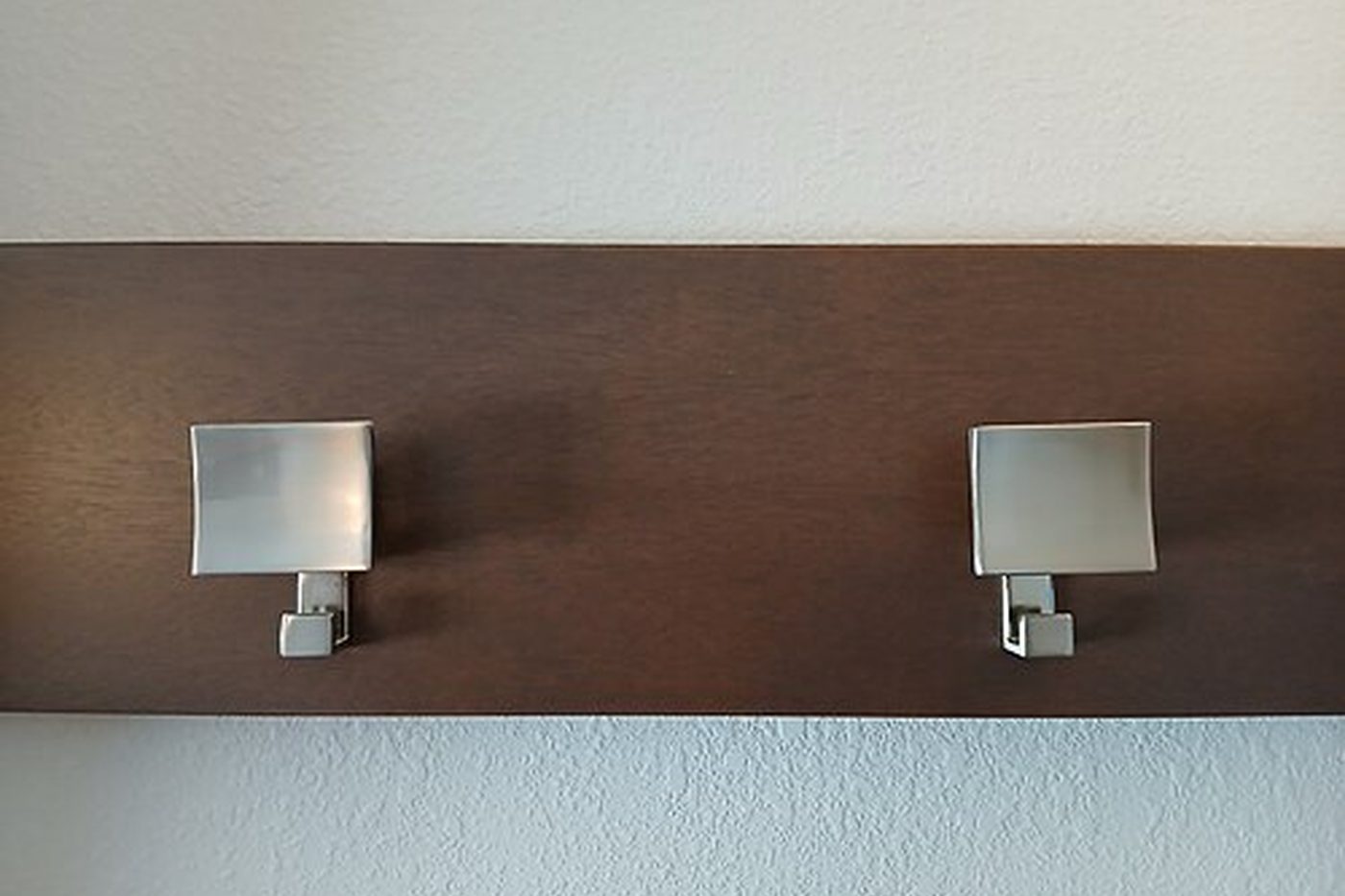 Two coat hooks on a wooden wall rail