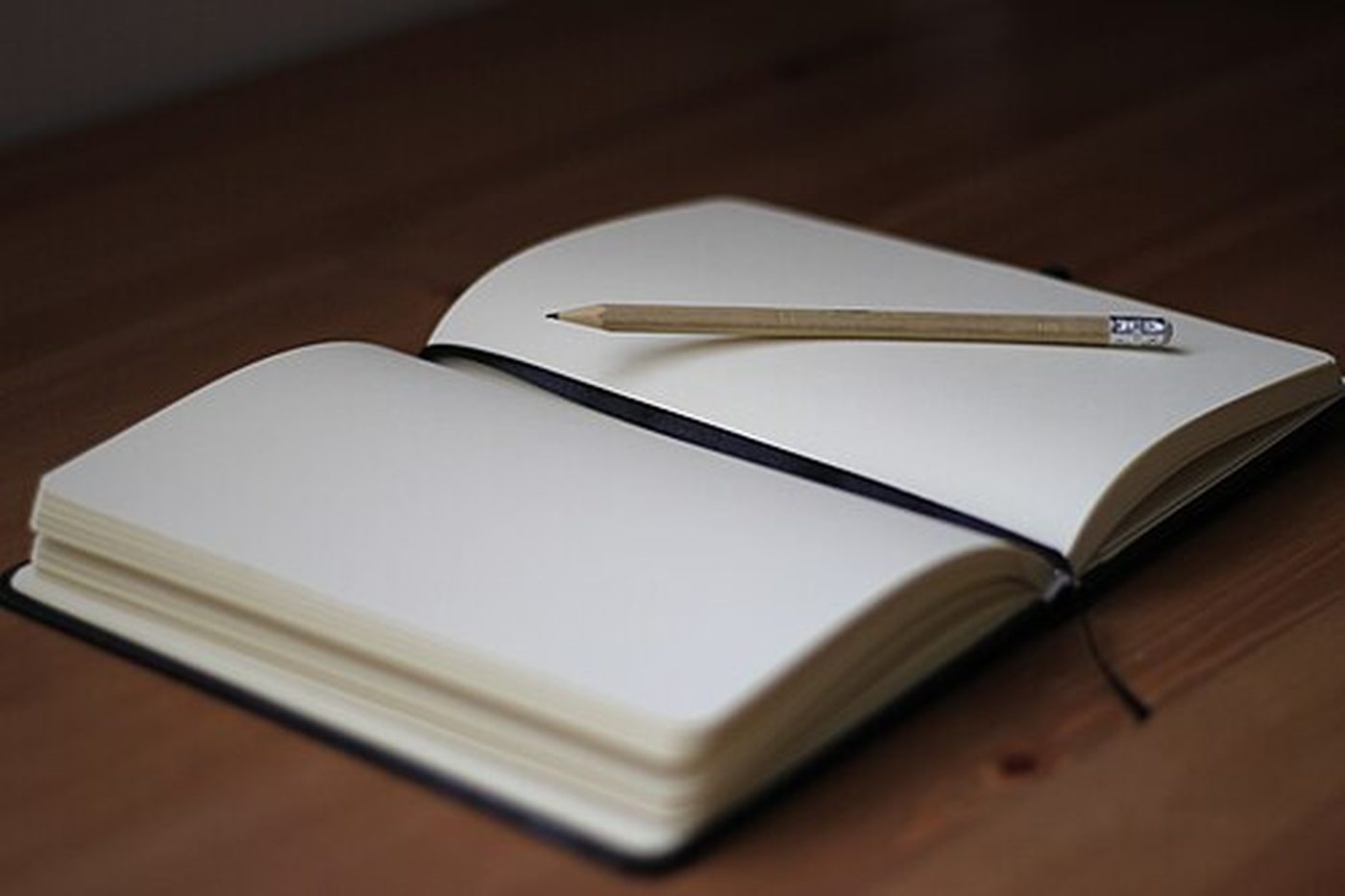 An open notebook with a pencil on a wooden desk