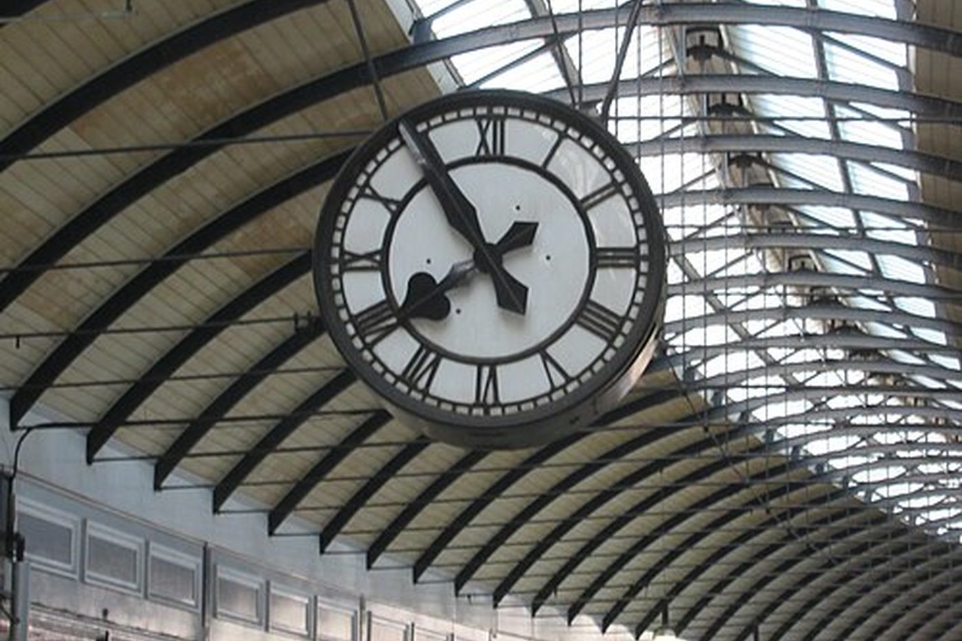 Eine große Bahnhofsuhr unter einem gewölbten Glasdach
